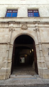 Fotografia de la façana de pedra del palau del Marqués de Villores, a Sant Mateu. En primera plana, l'entrada de l'edifici, un portal de gran alçada flanquejat per sengles columnes de pedra, coronat per un escut d'armes, sota dues finestres.
